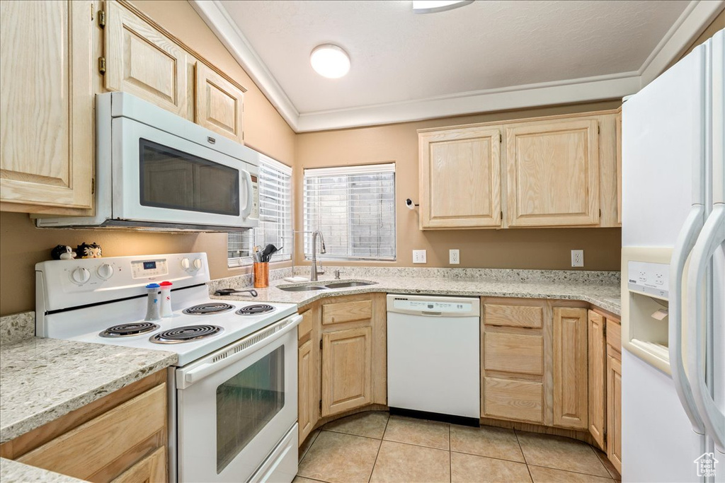 Kitchen featuring white appliances, light brown cabinetry, a sink, light tile patterned floors, and crown molding