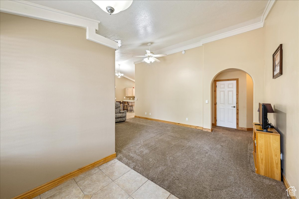 Empty room featuring a ceiling fan, arched walkways, ornamental molding, baseboards, and light colored carpet