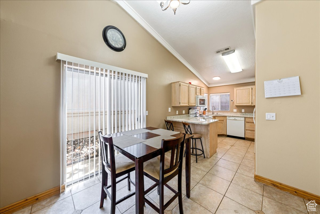 Dining room featuring vaulted ceiling, ornamental molding, baseboards, and light tile patterned floors