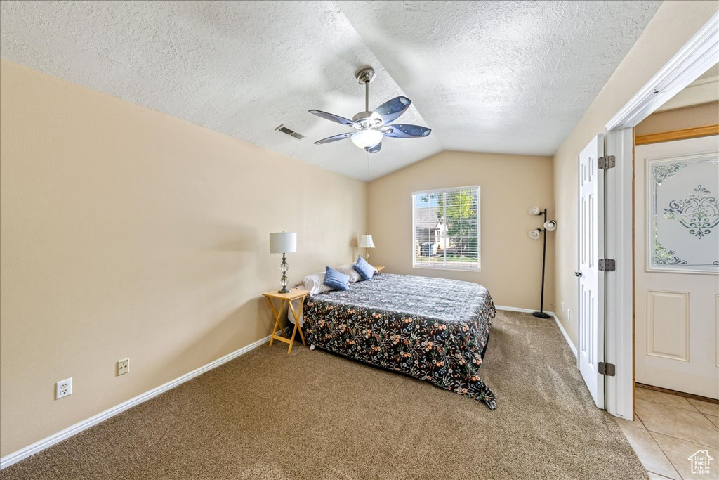 Bedroom with lofted ceiling, baseboards, light colored carpet, a textured ceiling, and a ceiling fan
