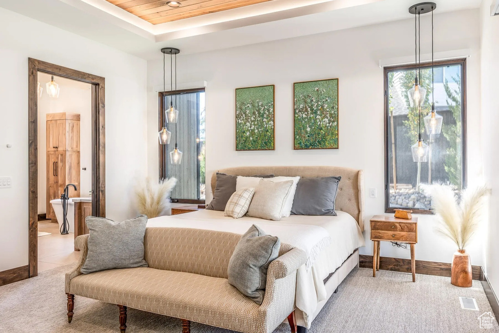 Bedroom with light carpet, multiple windows, connected bathroom, and a raised ceiling
