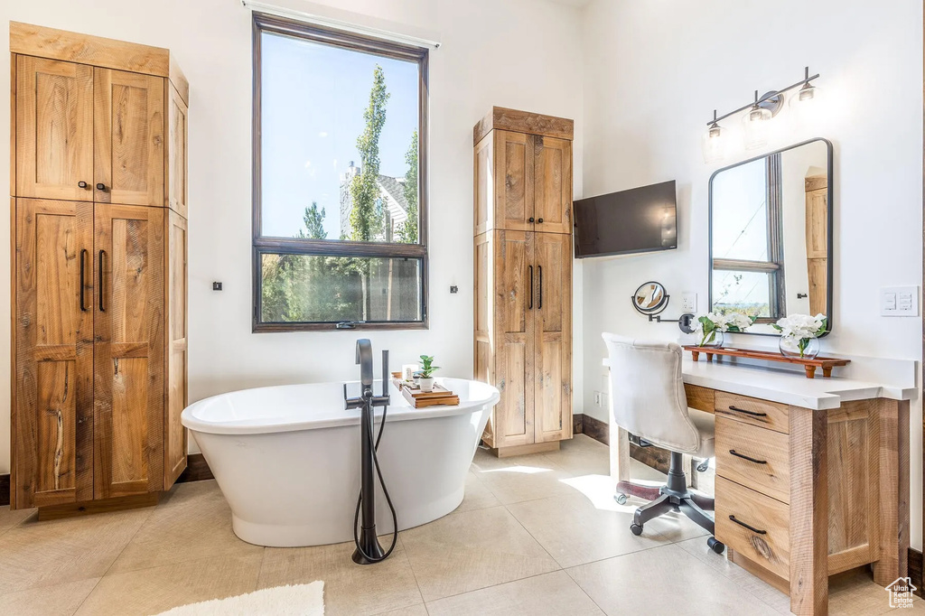 Bathroom featuring a freestanding tub, a closet, and tile patterned floors