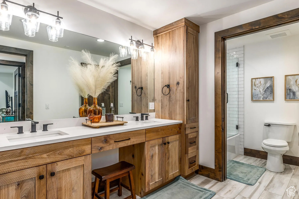 Bathroom featuring toilet, double vanity, wood finished floors, and baseboards