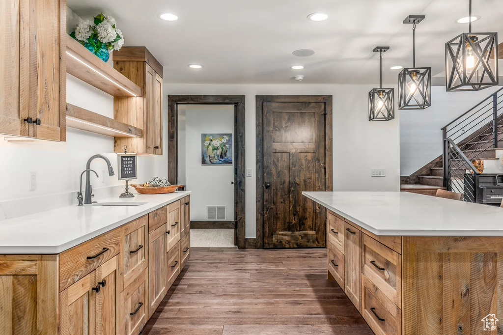 Kitchen featuring a sink, dark wood-style floors, light countertops, recessed lighting, and pendant lighting