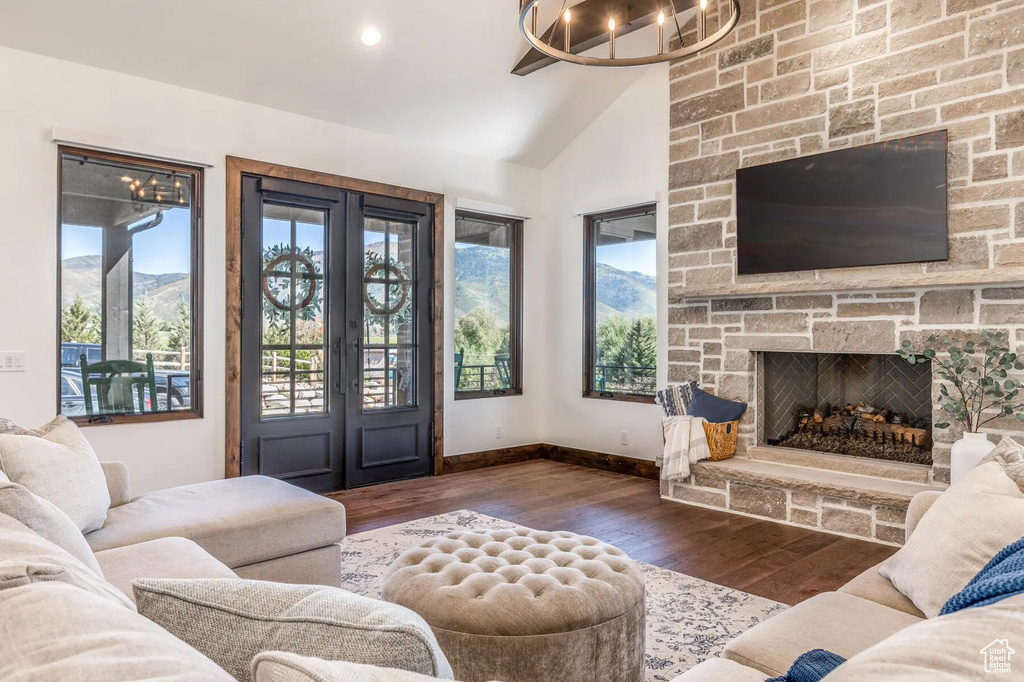 Living area featuring lofted ceiling, wood finished floors, baseboards, a fireplace, and a chandelier