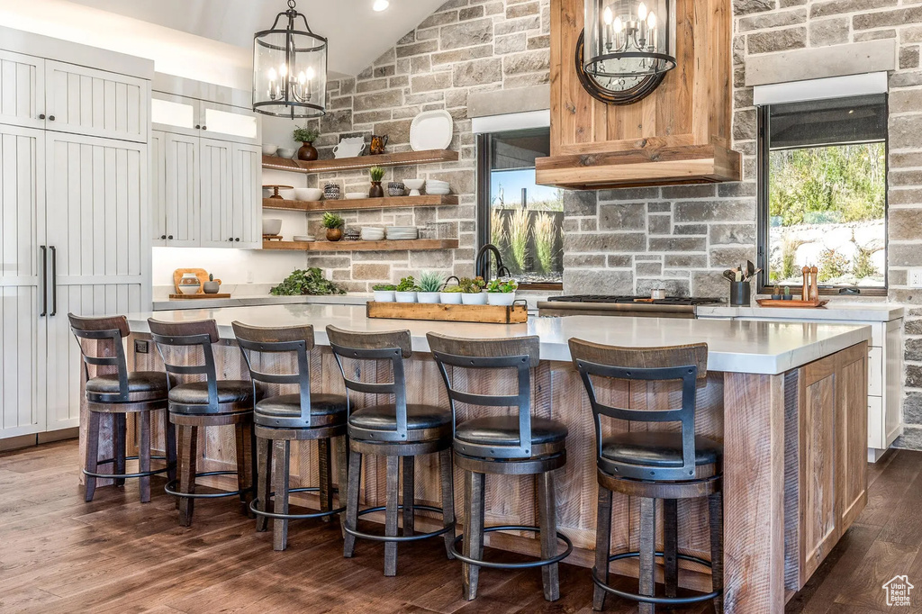 Bar area featuring lofted ceiling, dark wood-style floors, pendant lighting, a chandelier, and stainless steel gas stovetop