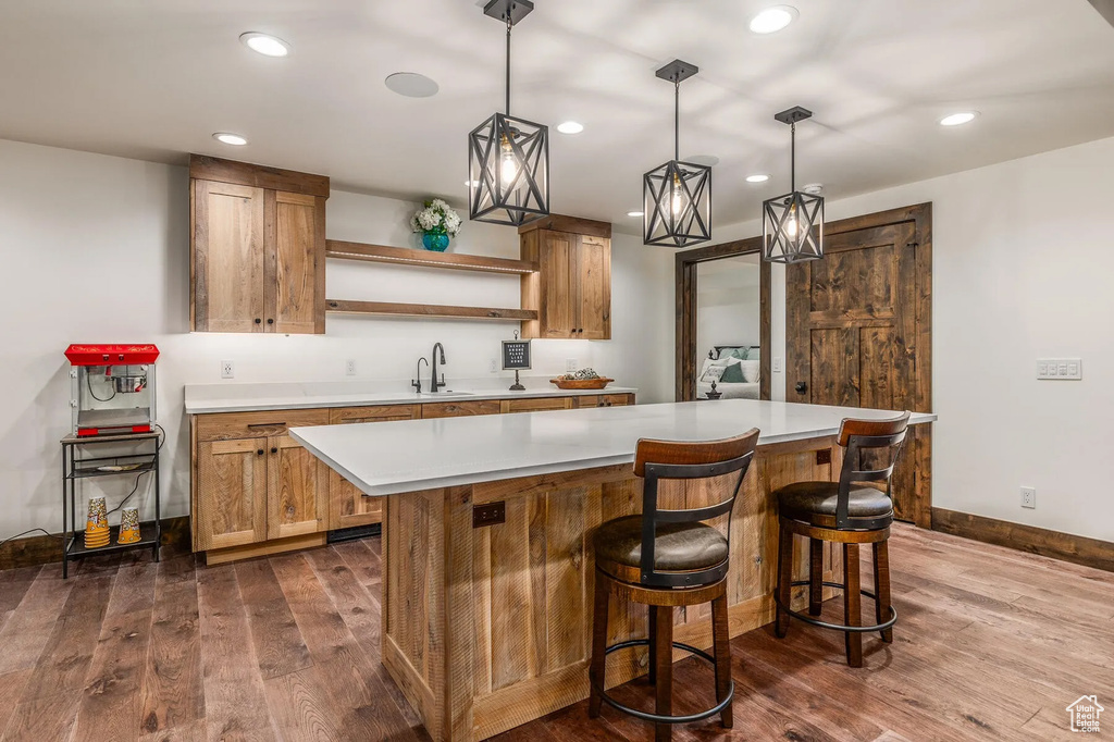 Kitchen featuring open shelves, dark wood-type flooring, light countertops, a kitchen island, and recessed lighting
