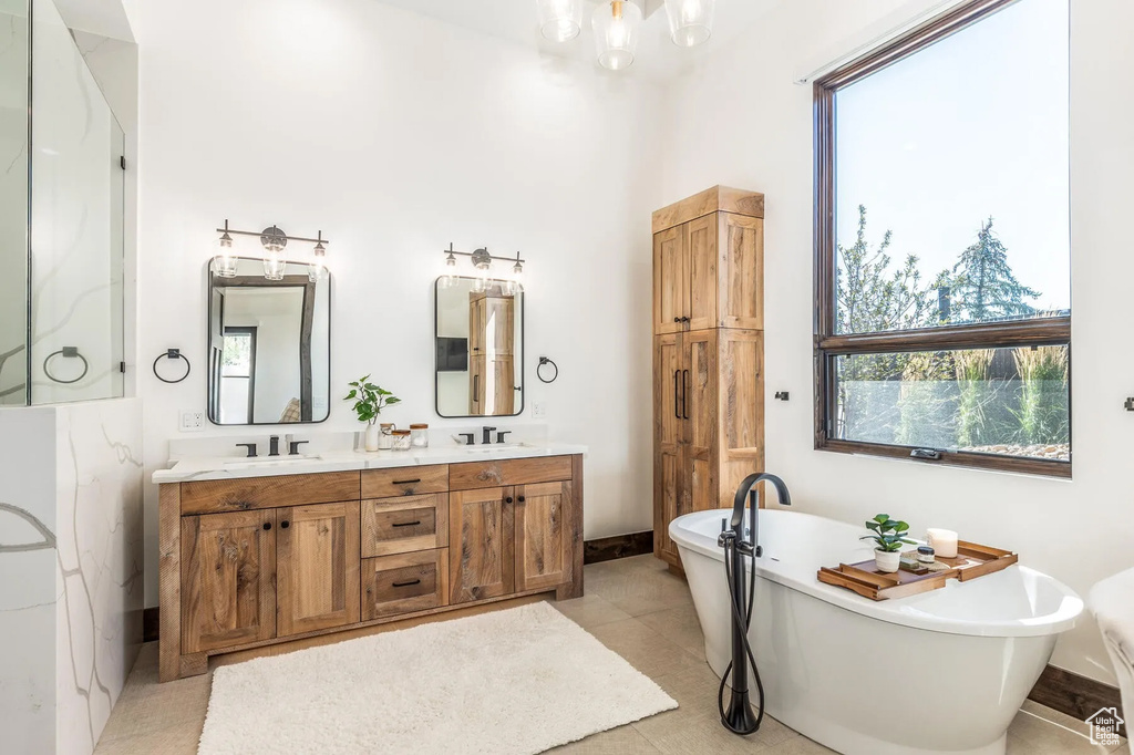 Bathroom with a freestanding bath, double vanity, a chandelier, baseboards, and a shower