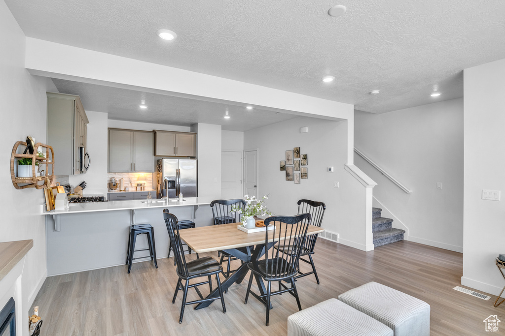 Dining room featuring stairs, light wood-type flooring, recessed lighting, a textured ceiling, and baseboards