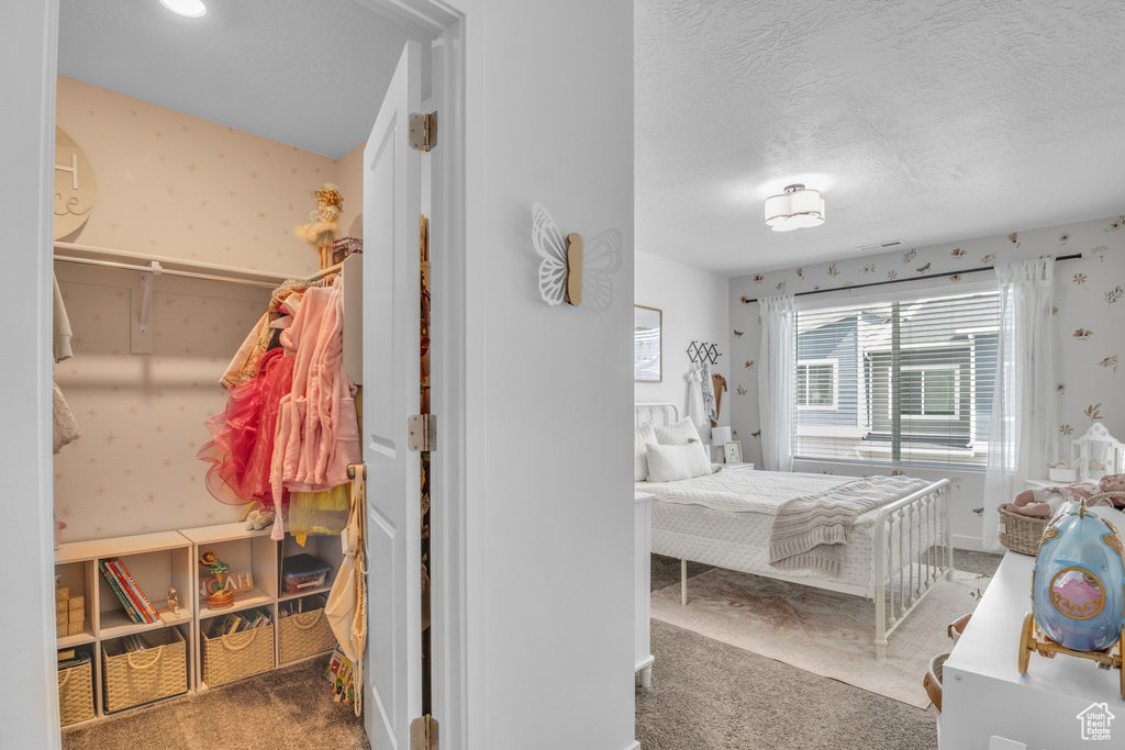 Carpeted bedroom with wallpapered walls and a textured ceiling