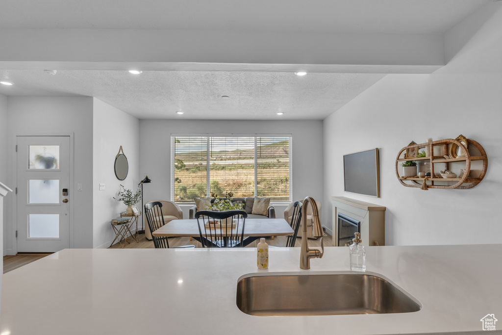 Kitchen with a sink, wood finished floors, recessed lighting, light countertops, and a textured ceiling