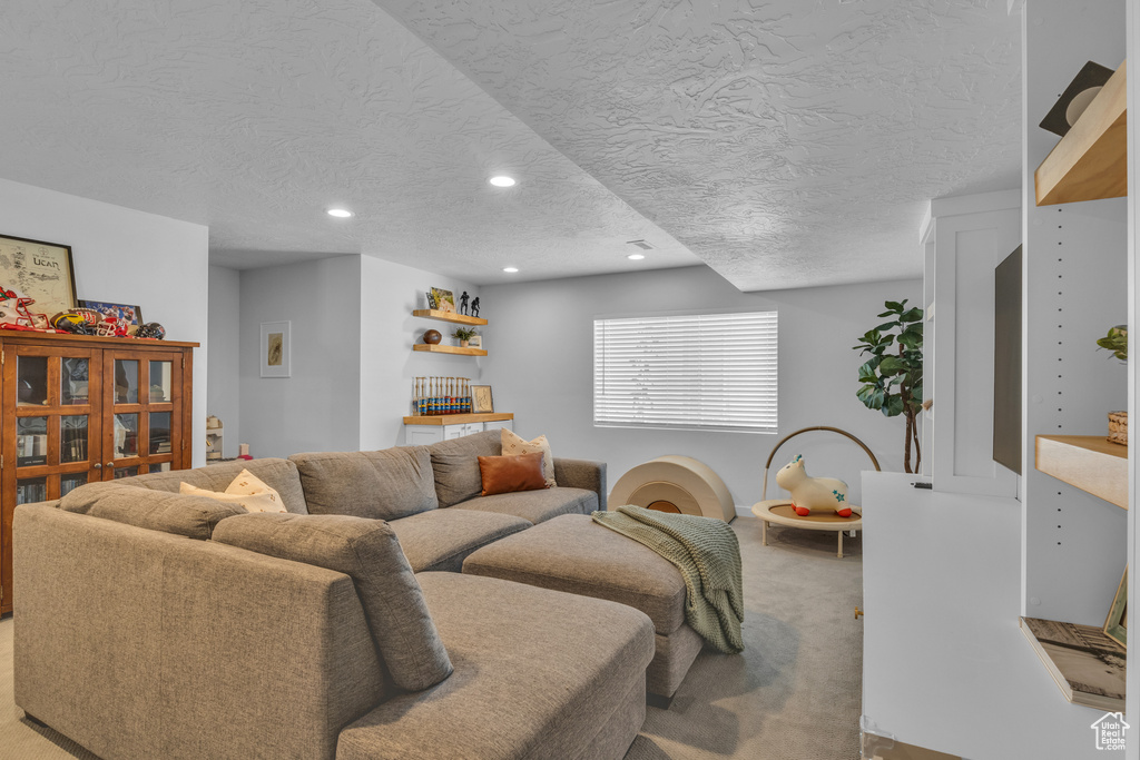 Living room featuring a textured ceiling, light colored carpet, and recessed lighting