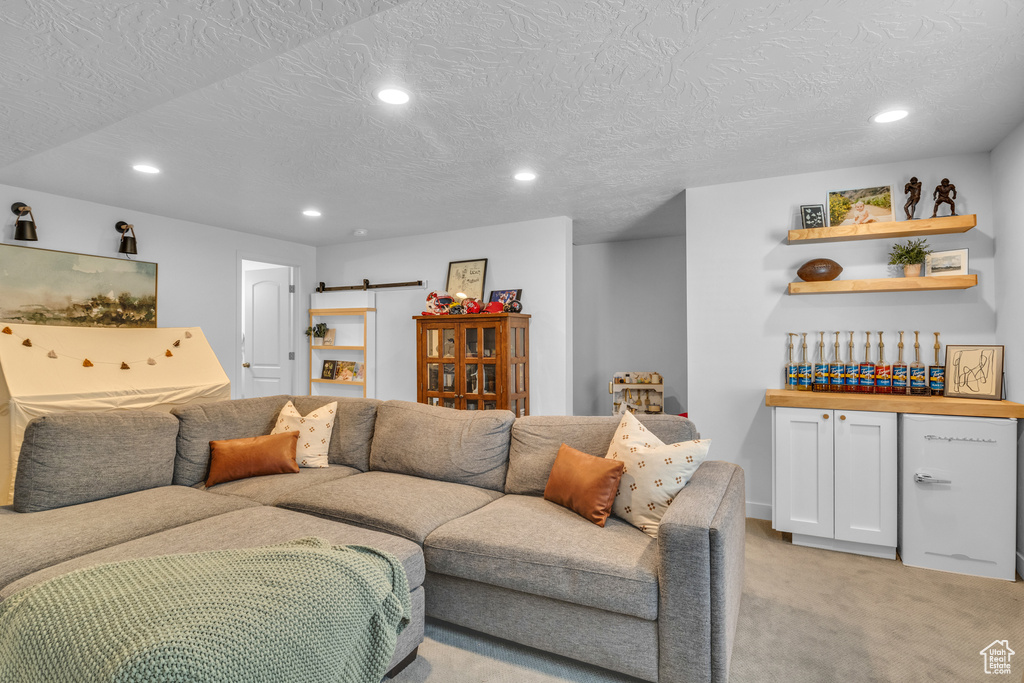 Living area with recessed lighting, light colored carpet, and a textured ceiling
