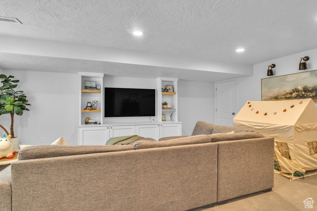 Living area with light carpet, recessed lighting, and a textured ceiling
