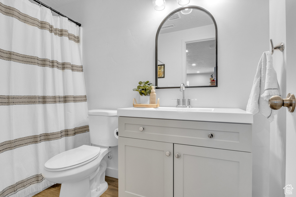 Full bathroom featuring toilet, wood finished floors, and vanity