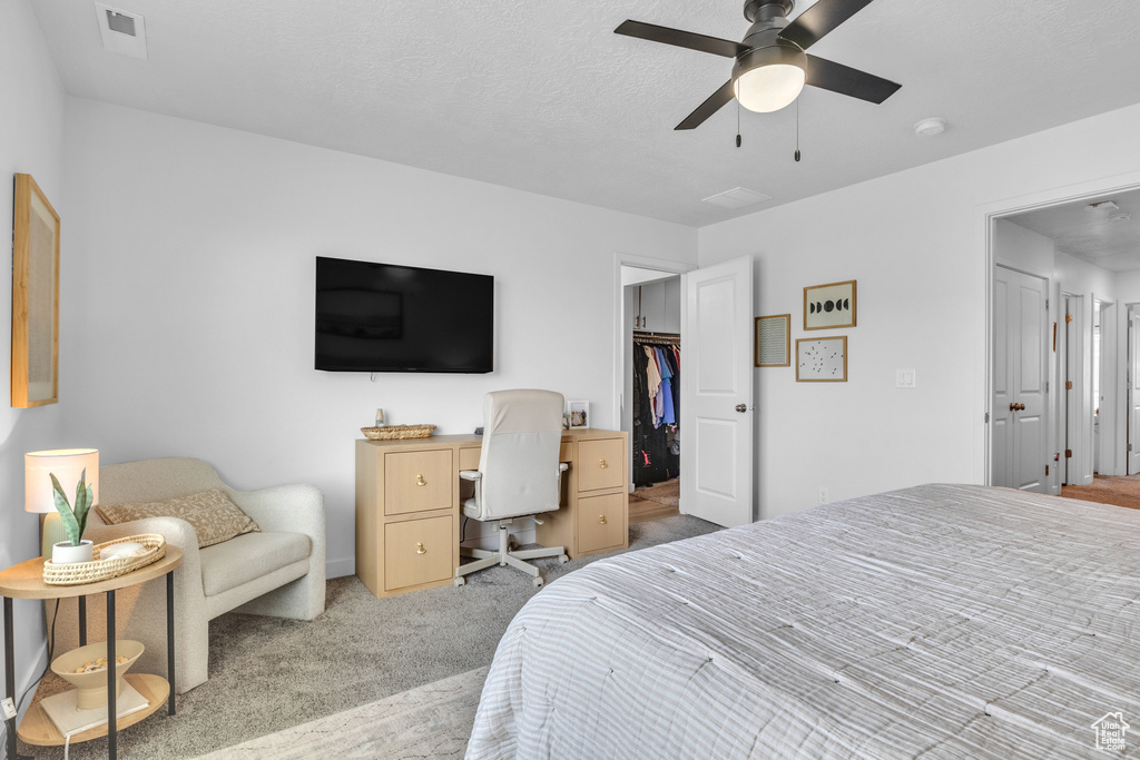 Carpeted bedroom featuring a spacious closet, a ceiling fan, and a closet