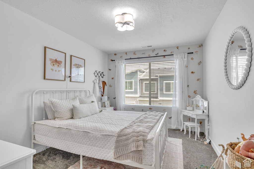 Bedroom featuring light colored carpet, baseboards, and a textured ceiling