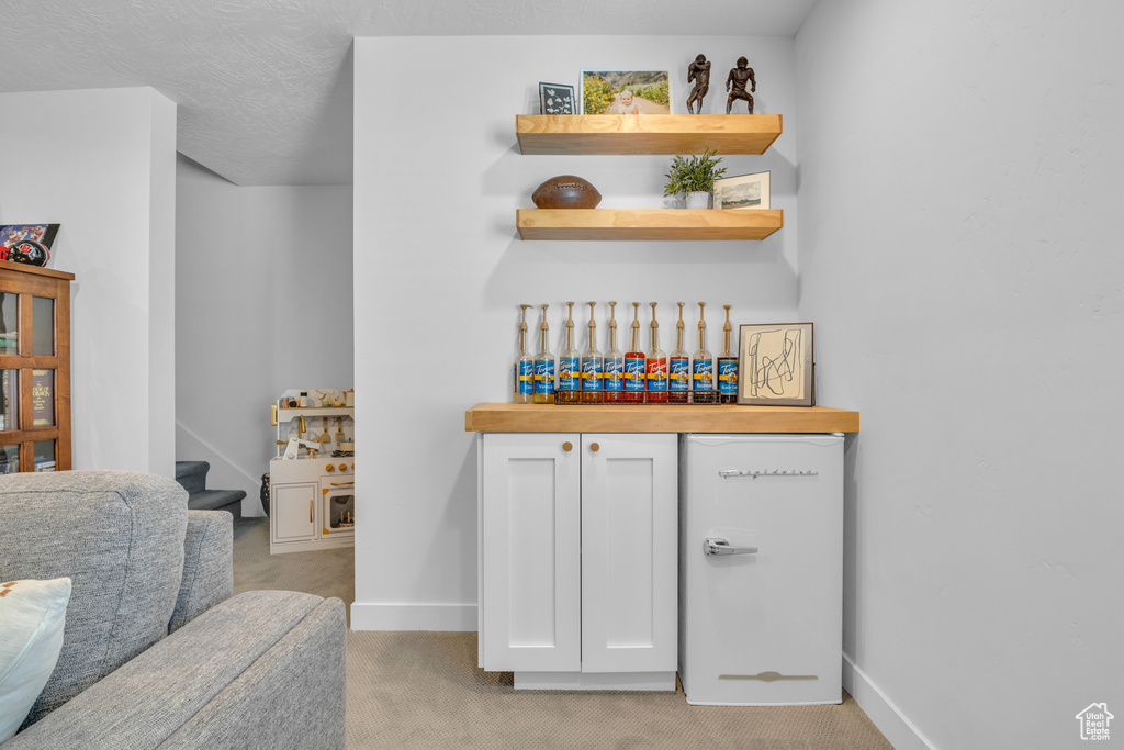 Indoor dry bar featuring light colored carpet and baseboards