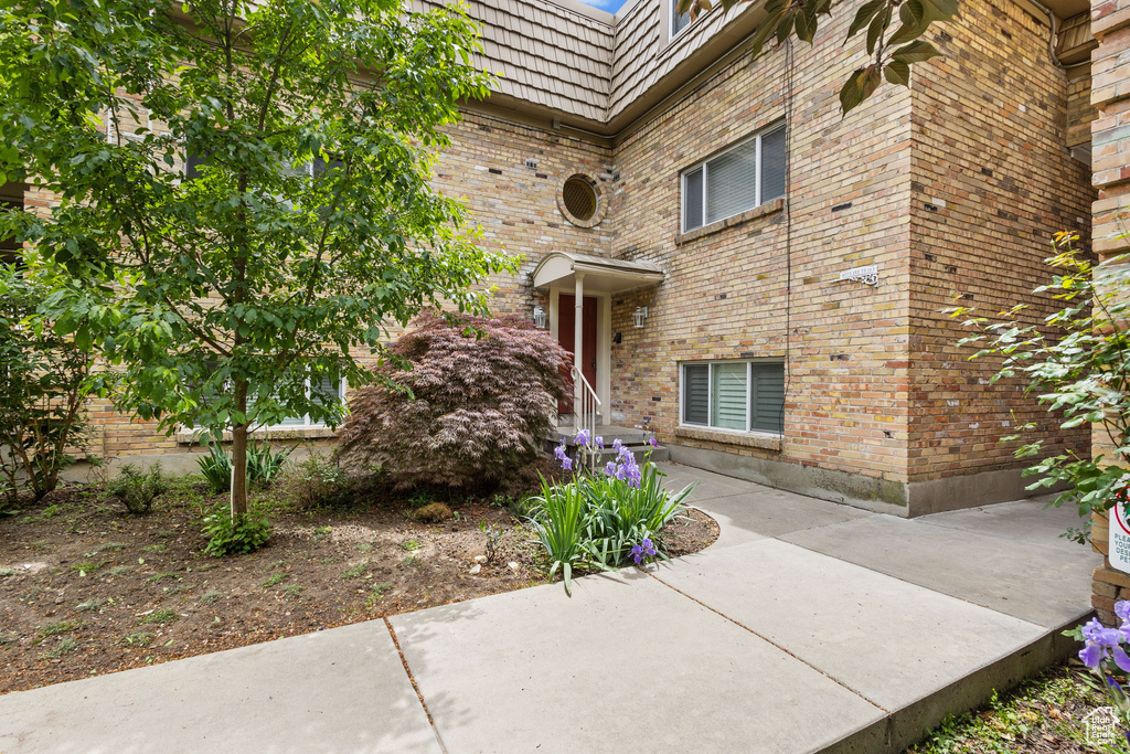 Doorway to property featuring brick siding and mansard roof