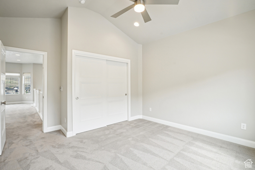 Unfurnished bedroom featuring light carpet, vaulted ceiling, baseboards, a closet, and recessed lighting