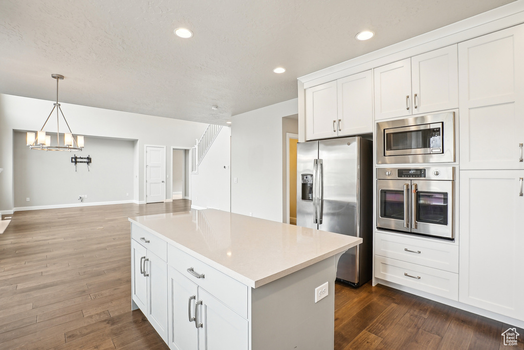 Kitchen featuring stainless steel appliances, a chandelier, dark wood-style flooring, white cabinetry, and light countertops