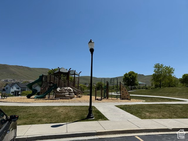Community playground featuring a mountain view and a lawn