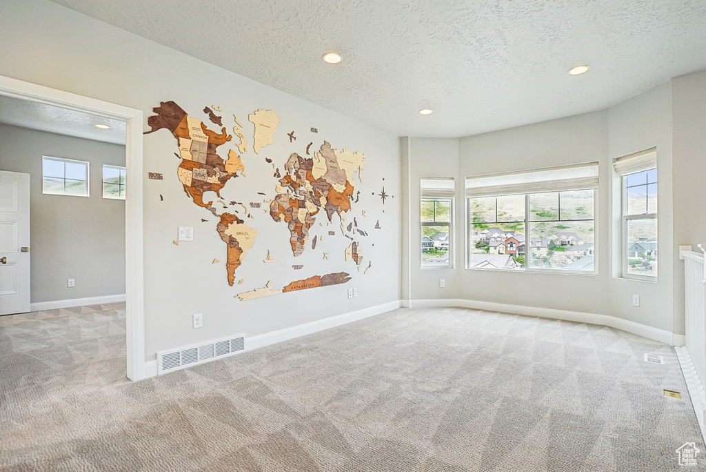 Carpeted empty room with a textured ceiling, recessed lighting, and baseboards