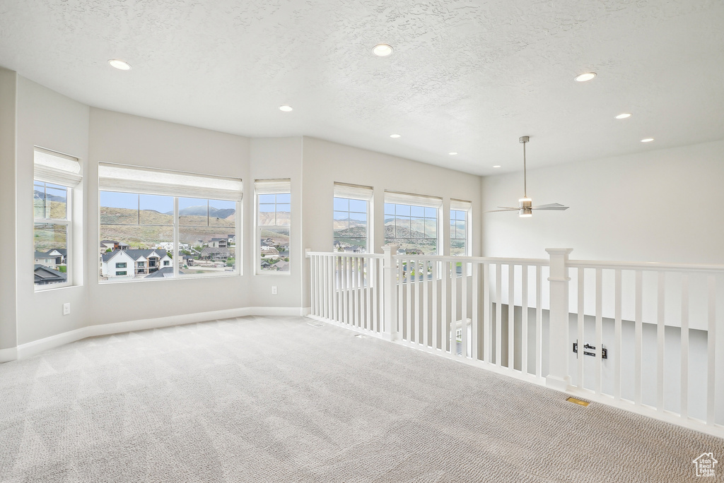 Empty room featuring carpet floors, recessed lighting, baseboards, a textured ceiling, and ceiling fan