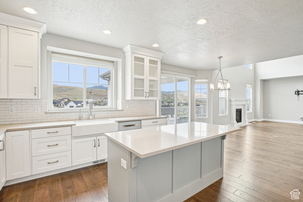 Kitchen featuring a sink, decorative backsplash, light countertops, a textured ceiling, and white cabinets