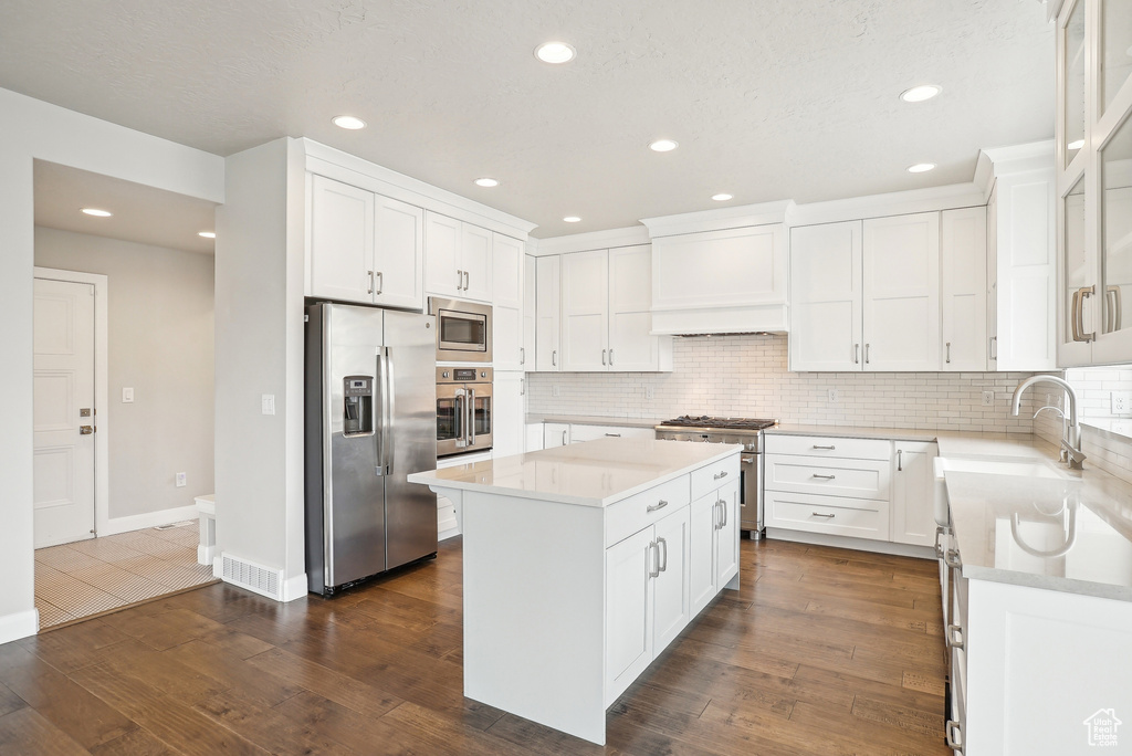Kitchen with appliances with stainless steel finishes, light countertops, tasteful backsplash, a kitchen island, and recessed lighting
