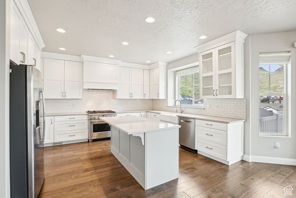 Kitchen featuring appliances with stainless steel finishes, light countertops, backsplash, white cabinetry, and recessed lighting