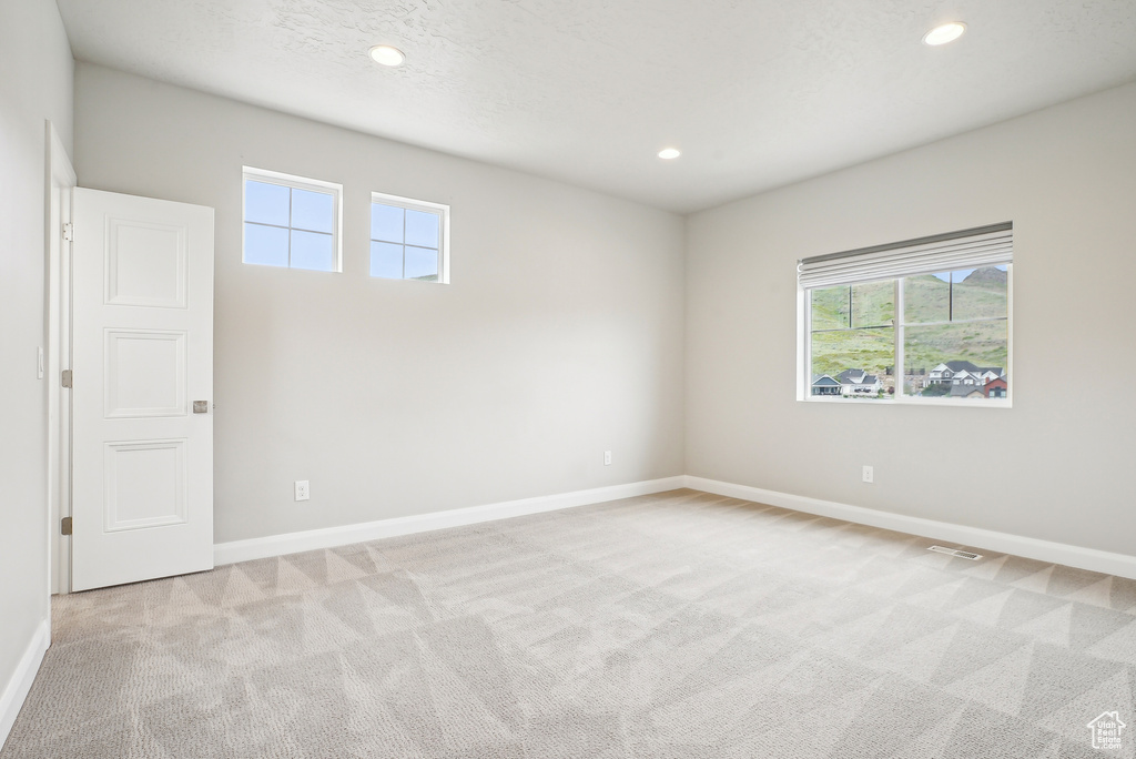 Spare room with light carpet, healthy amount of natural light, baseboards, and recessed lighting