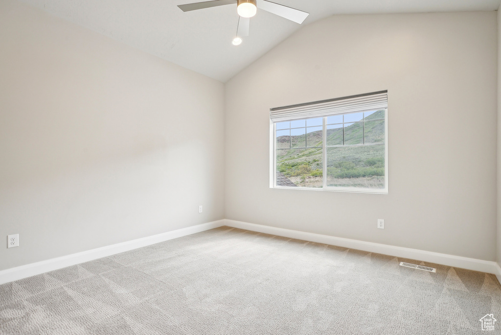 Carpeted spare room featuring a ceiling fan, baseboards, and vaulted ceiling