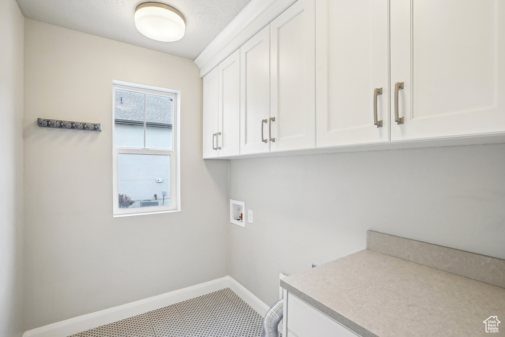 Clothes washing area featuring cabinet space, hookup for a washing machine, and baseboards