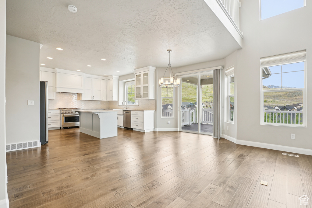 Unfurnished living room with a chandelier, a textured ceiling, dark wood-type flooring, recessed lighting, and baseboards