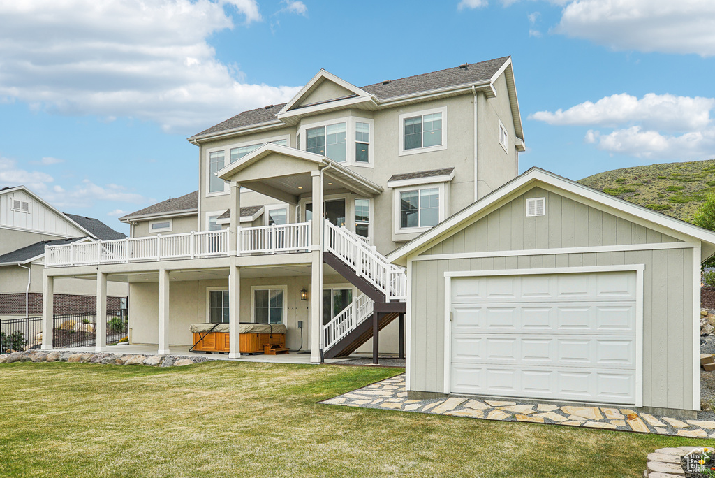 View of front facade featuring a hot tub, a front yard, stairway, and a wooden deck