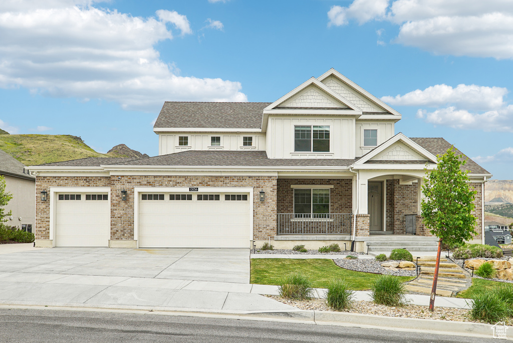 View of front of home with concrete driveway, a garage, a porch, board and batten siding, and a front yard