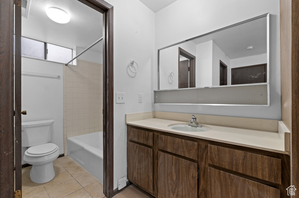 Full bathroom with toilet, tile patterned flooring, vanity, and  shower combination
