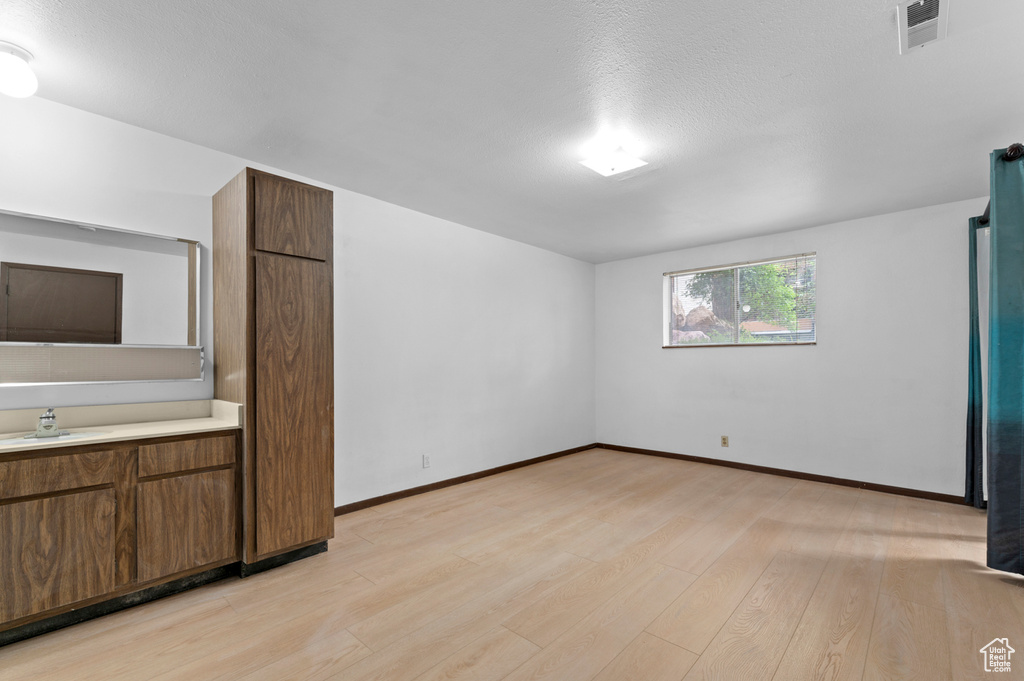 Unfurnished room featuring light wood-style floors, a sink, and baseboards