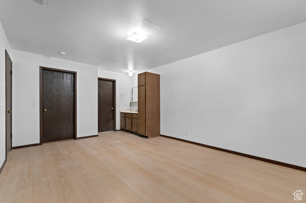 Unfurnished bedroom featuring light wood-style flooring, two closets, and baseboards