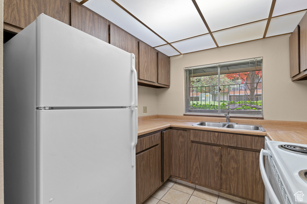 Kitchen with white appliances, a sink, light countertops, and light tile patterned floors
