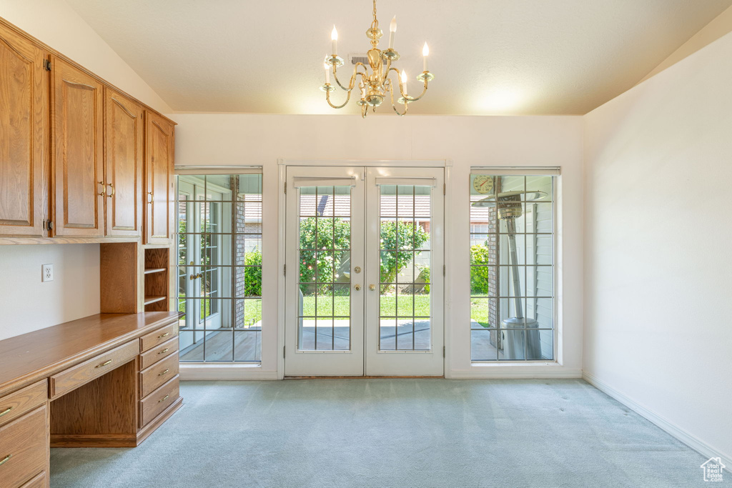 Entryway featuring light carpet, a chandelier, french doors, and a desk