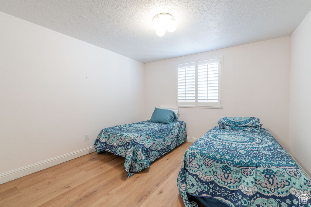 Bedroom with wood finished floors, baseboards, and a textured ceiling