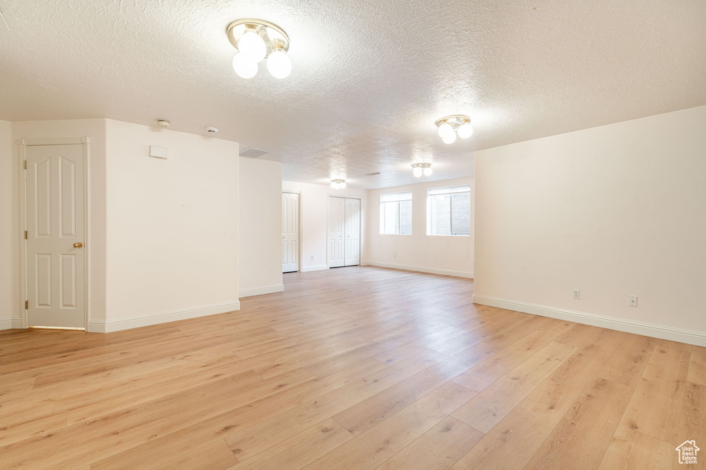 Spare room with light wood finished floors, a textured ceiling, and baseboards