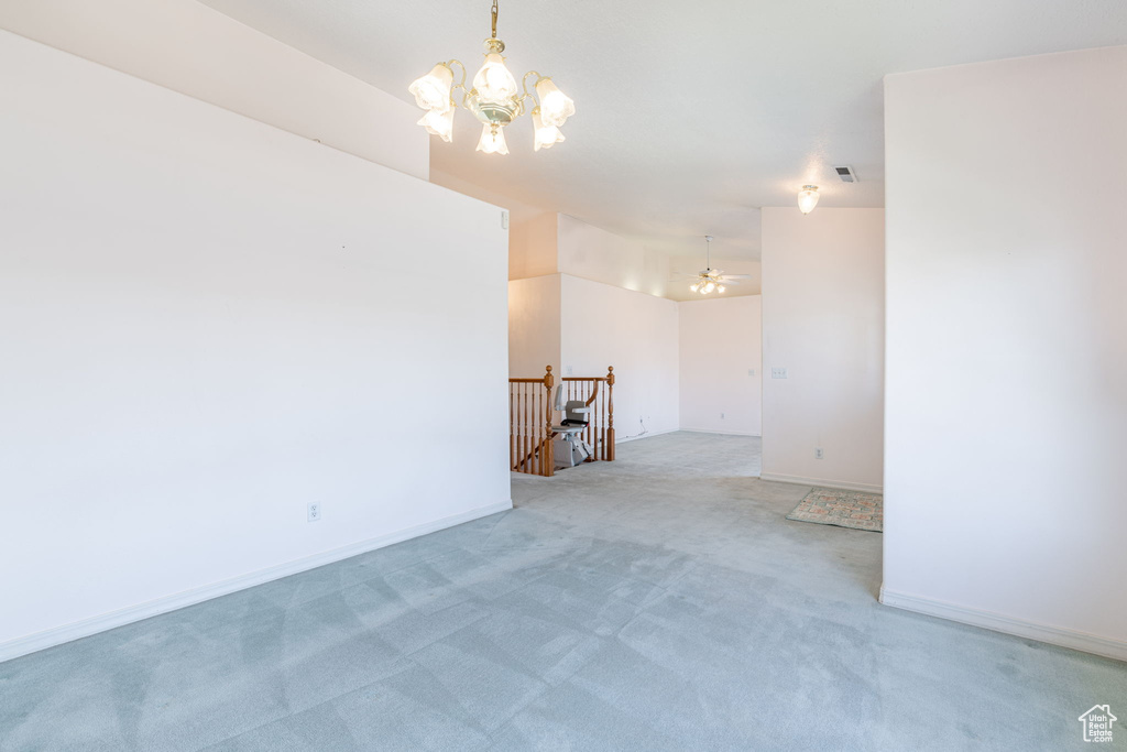 Spare room with a chandelier, light colored carpet, and baseboards