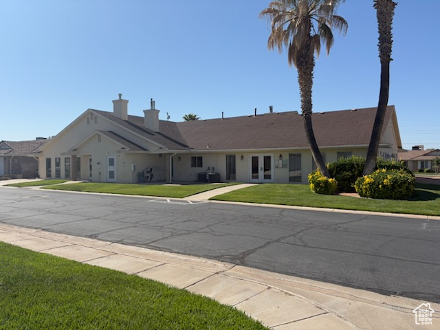 Ranch-style house with french doors, a front lawn, and a chimney