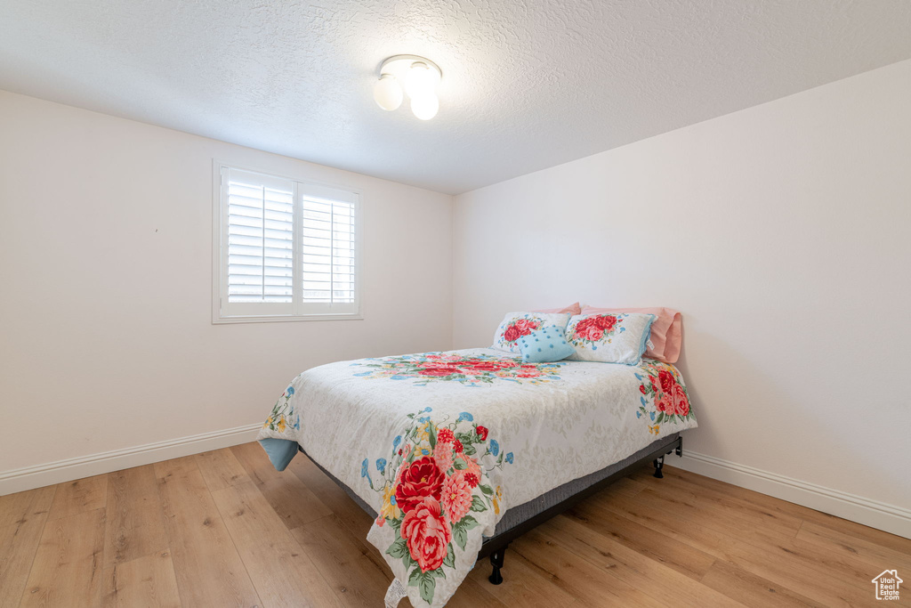 Bedroom with wood finished floors, baseboards, and a textured ceiling