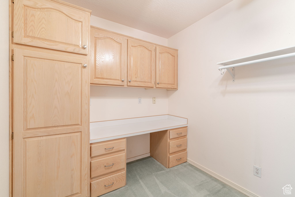 Unfurnished office with built in desk, light colored carpet, and baseboards