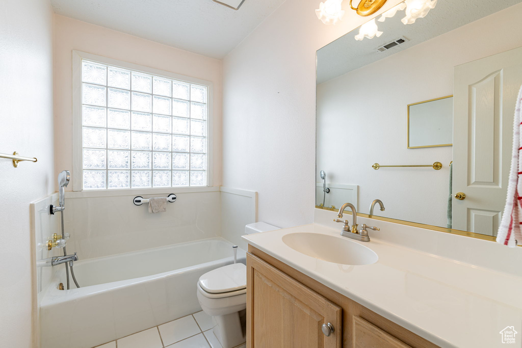 Full bathroom featuring a garden tub, vanity, toilet, and tile patterned floors