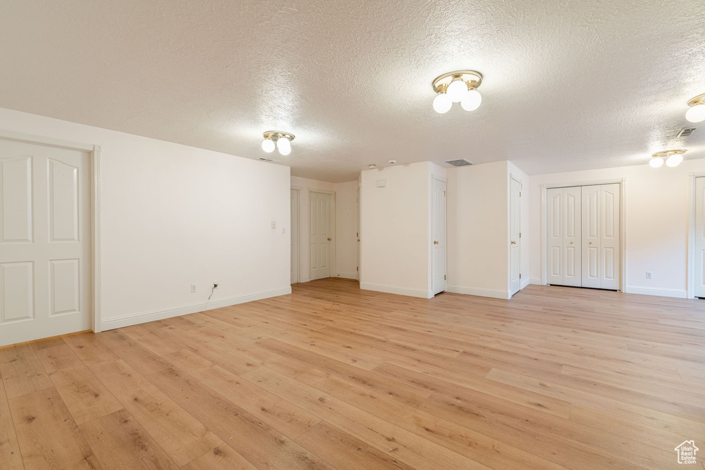 Unfurnished room featuring a textured ceiling, light wood-style floors, and baseboards